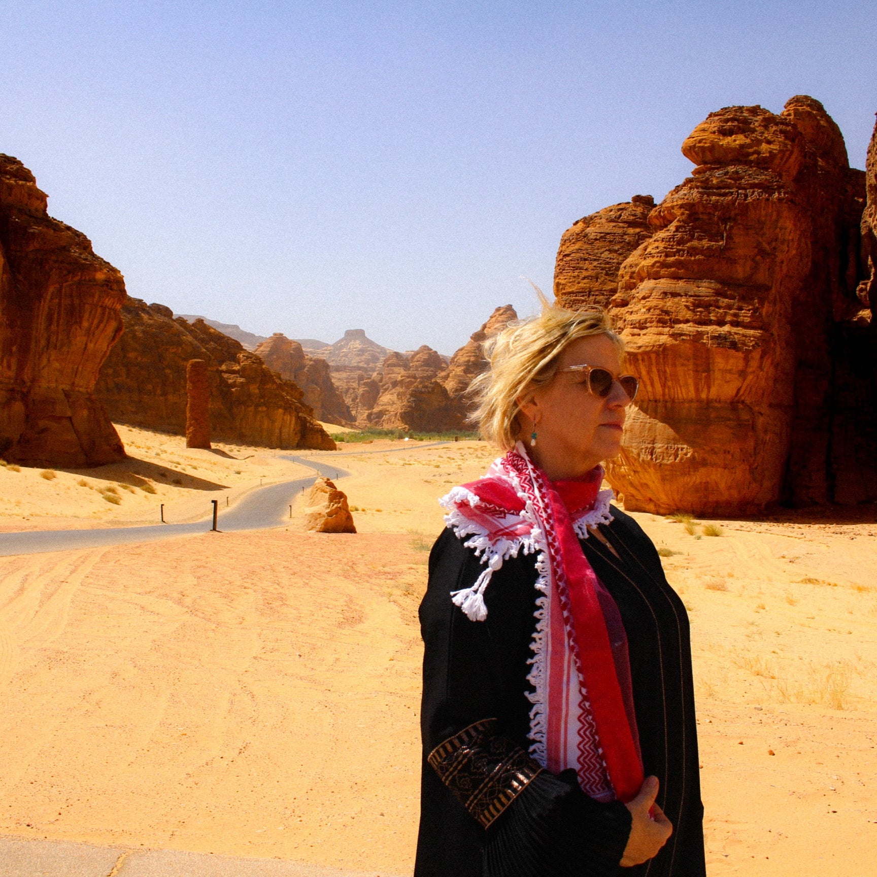 Woman wearing beautiful red keffiyeh scarf in al ula desert saudi arabia artisan handmade