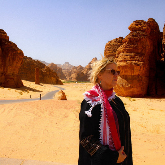 Woman wearing beautiful red keffiyeh scarf in al ula desert saudi arabia artisan handmade