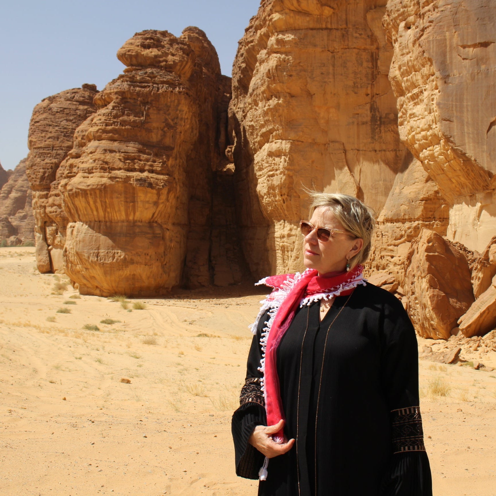 Woman wearing beautiful red keffiyeh scarf in al ula desert saudi arabia
