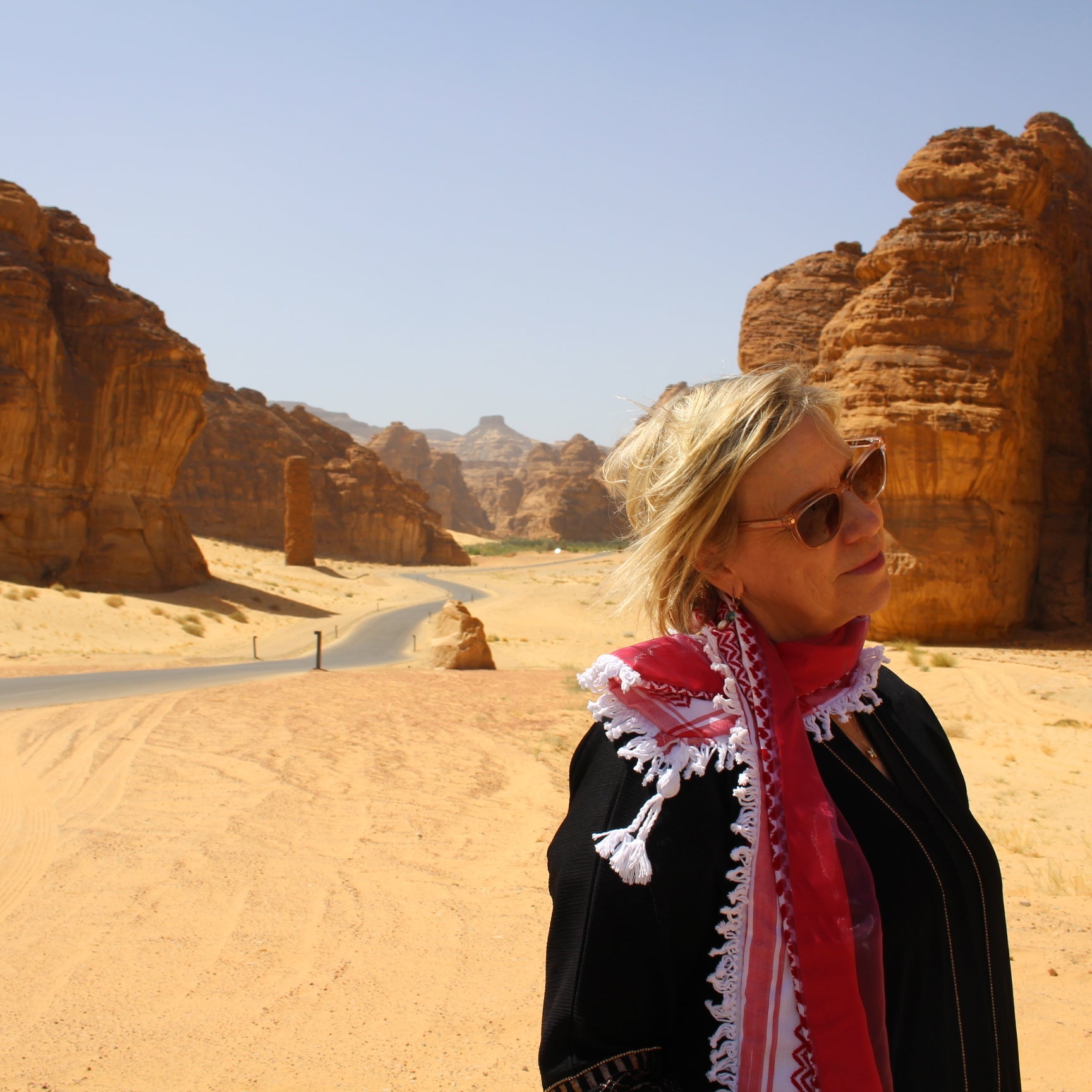 Woman wearing beautiful red keffiyeh scarf in al ula desert saudi arabia