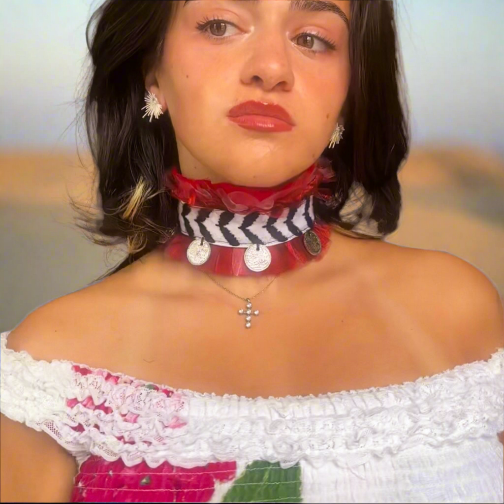 Woman wearing a colorful choker with coins in a white top and floral design.